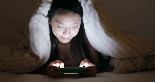 Woman Using Cellphone Under Blanket at Night alt