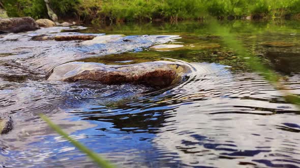 Mountain stream with stones and sky reflections