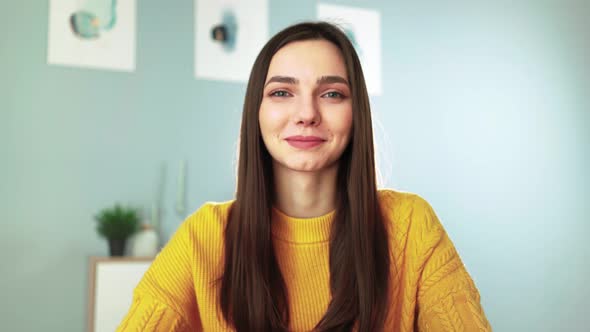 Happy Woman in Yellow Sweater Smiling and Chatting on Webcam with Her Followers alt