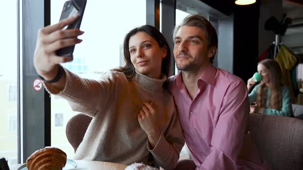 A Young Beautiful Couple Takes a Selfie in a Cafe