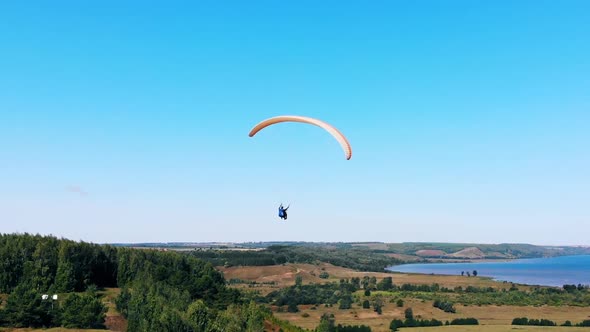 Male Athlete Flying with a Glider in Blue Sky alt