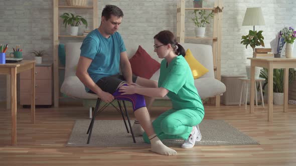 Nurse Helps To Pull the Bandage on the Knee of a Man Athlete alt