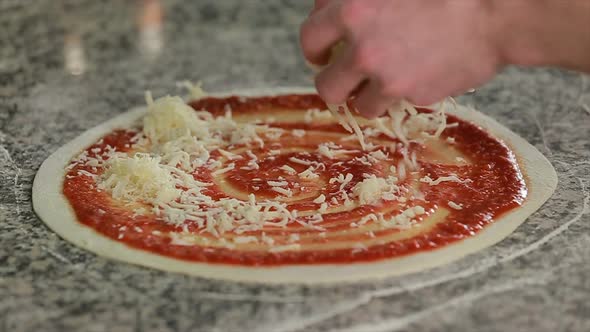 Putting Cheese Topping on Pizza Dough Already Coated with Tomato Sauce alt