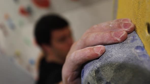 Close-up of a mans hands has he climbs in an indoor climbing gym. alt