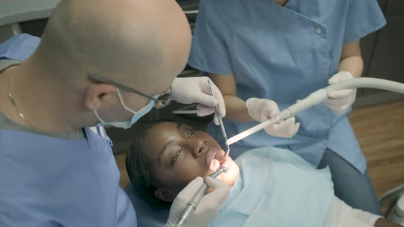Woman receiving dental treatment, dentist with dental drill alt