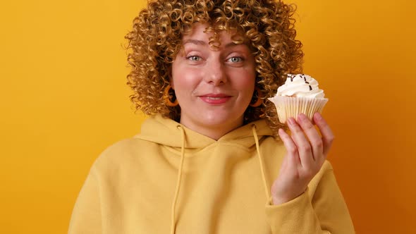 Young Pretty Woman Smiling Cheerfully Feeling Happy and Holding Tasty Cake Over Bright Yellow Color