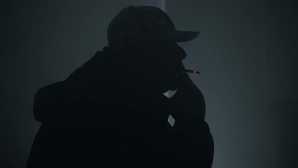 A Man Smokes A Cigarette In A Dark Room alt