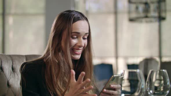 Excited Woman Using Smartphone in Restaurant. Business Woman Enjoy Good News alt