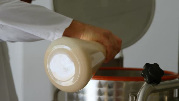 Male worker pouring liquor in distillation tank alt