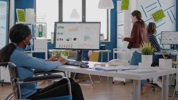 African Paralyzed Businesswoman with Protection Mask Typing Reports on Pc alt