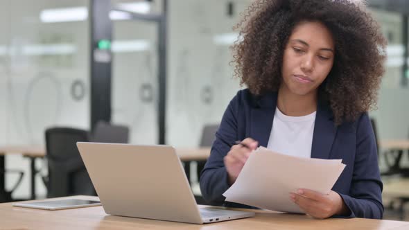 African Businesswoman Working on Laptop and Documents  alt
