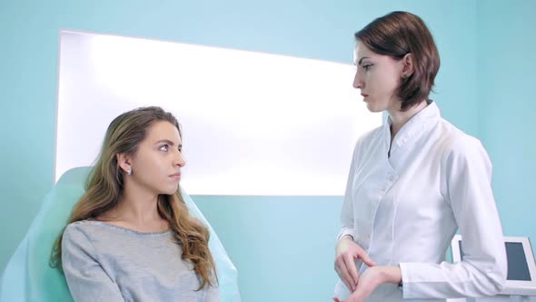 A Cosmetologist and a Patient in a Bright Office at a Consultation Discuss Treatment. Woman