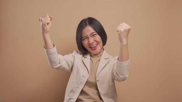 Confident asian business woman happy and make winning gesture standing isolated