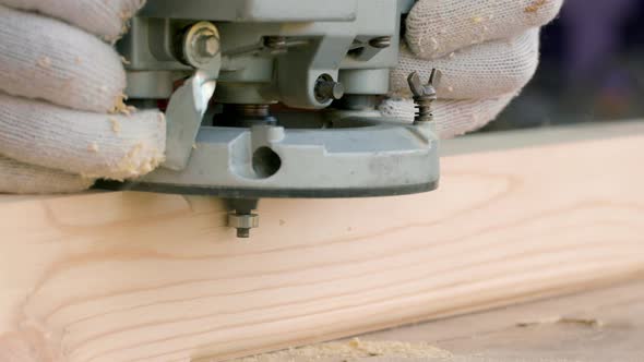 Joiner Cuts Off the Sharp Corners of a Wooden Beam Using a Milling Machine alt