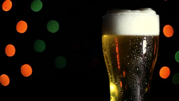 A Glass of Cold Beer on a Black Background with Colored Lights alt