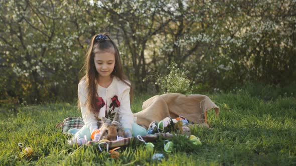 The Girl in the Yard Sitting on the Grass on a Background of Flowering Trees and Decorated with alt
