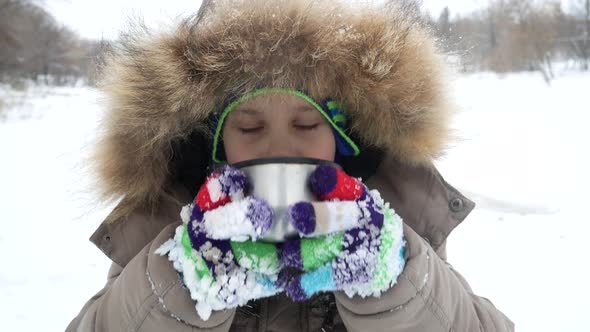 A Cute Boy 56 Years Old Drinks Tea From a Thermos in a Winter Park on a Walk alt