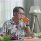 Asian Man Enjoys Drinking Orange Juice While Preparing Healthy Food At Home - VideoHive Item for Sale