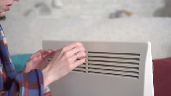 Close Up Young Woman Freezes in the Living Room and Heats Herself Next To an Electric Heater alt