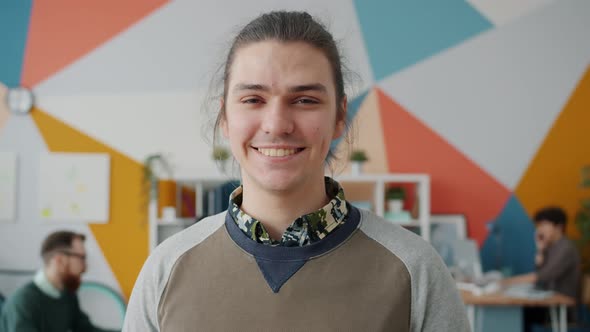 Portrait of Attractive Young Man Employee Standing in Office Smiling Looking at Camera alt