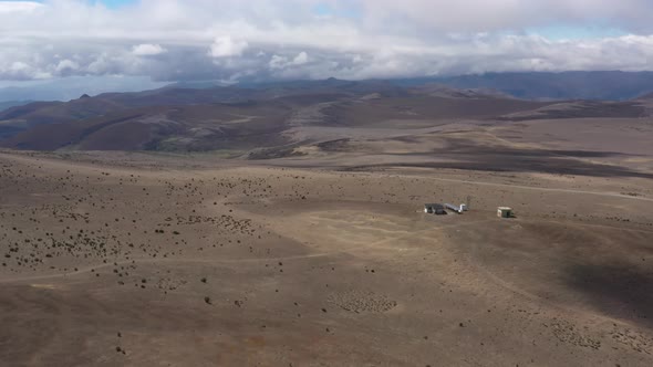 Aerial view of a small house or weatherstation with solar panels and an antennea on a large plain alt