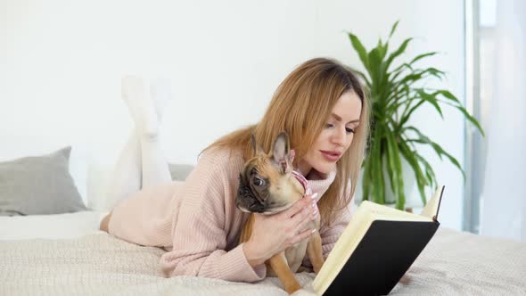 A Young Woman in a Cozy Powder Pink Sweater and White Stockings Lying on the Bed with Her Dog and alt