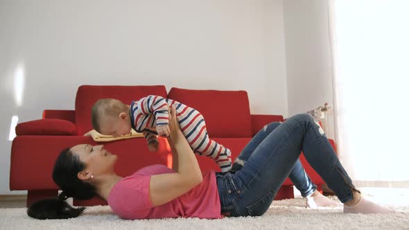 Mother Playing with Baby Son at Home Lifting Him alt