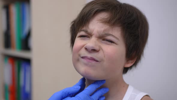 Headshot Portrait of Sad Caucasian Boy with Painful Throat Sitting in Hospital As Pediatrician Doing alt