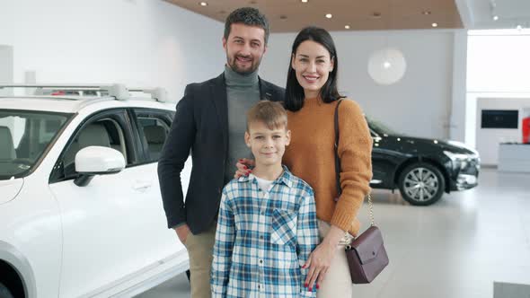 Portrait of Happy Family Woman, Man and Child in Car Showroom Smiling Looking at Camera alt