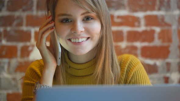 Attractive Young Happy Woman with Mobile Phone and Laptop