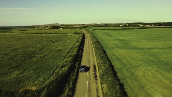 The car is moving in the left lane. Outside the city through the fields.