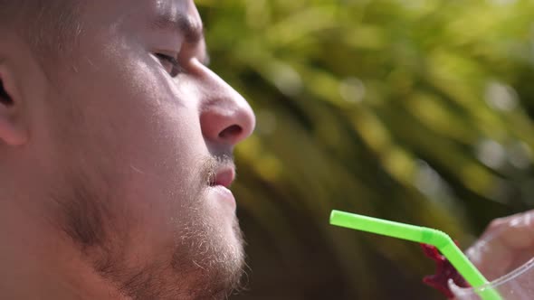 Young Bearded Man Drinking a Cocktail From a Plastic Tube Closeup