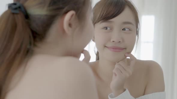 Beauty young asian woman smiling look at mirror of checking skin care caucasian with wellness. alt