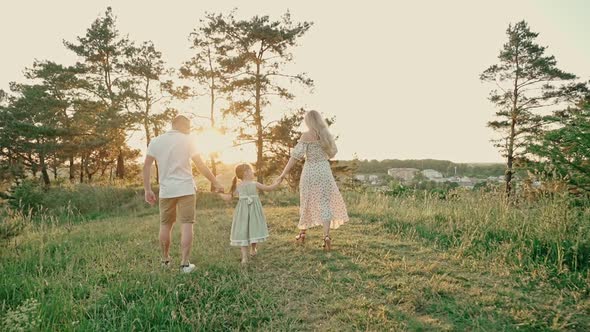 Young Married Couple with Cute Little Girl Spend Time Together Outdoors in the Forest alt