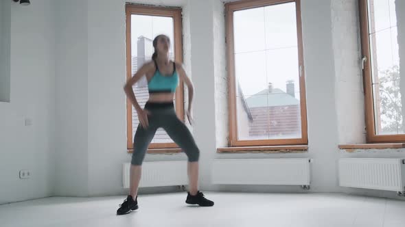 Young Fit Girl in Sportswear Does Exercises in Bright Room
