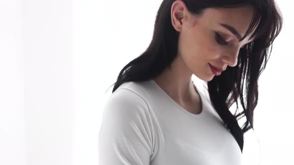 Pregnant Woman Touching Baby Belly In White Interior alt