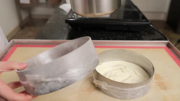 Woman Hands Arranges Cake Cream Into Cake Mold Using a Metal Spatula alt