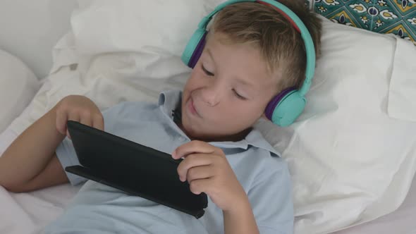 Kid relaxing with tablet PC at home alt