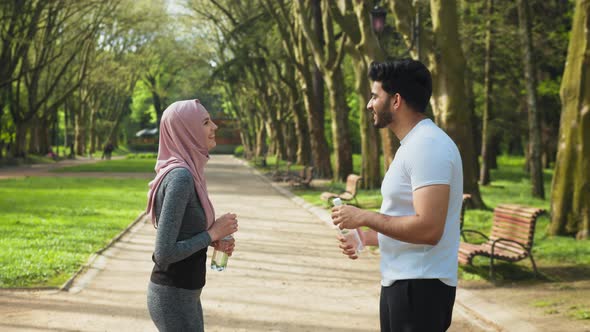 Happy Muslim Man and Woman in Hijab Giving High Five to Each Other Smiling and alt