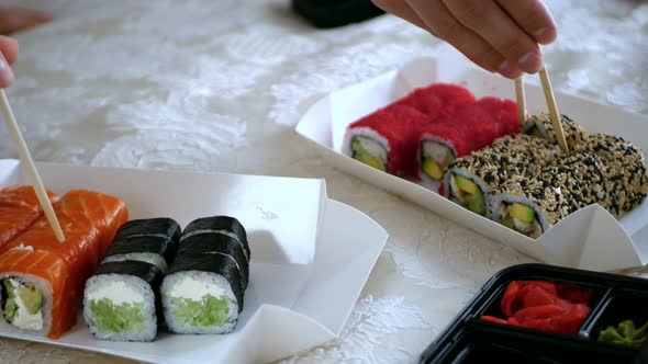 The Process of Eating Sushi on an Embroidered Blanket on the Bed