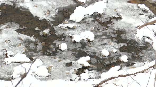 Slow motion icy cold flowing river water running through ice in Niagara escarpment, Canada alt