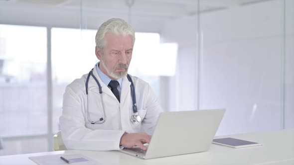 Focused Old Senior Doctor Working on Laptop alt