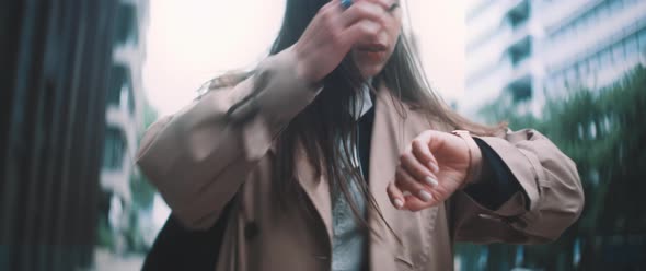 Woman checks watch then fixes hair while walking alt