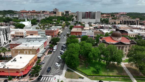 Wide aerial of downtown San Marcos Texas with Hays County Courthouse and TX State University in dist alt