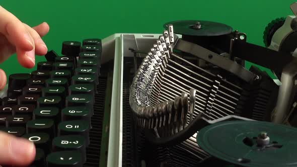 The girl is typing on a retro typewriter on a green background. Chromakey. alt