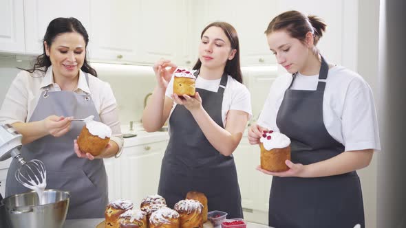 a Mother and Daughters Decorate Icing Dried Berries and Flowers Easter Cakes alt
