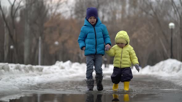 Boy and Girl Walking in a Puddle at Winter