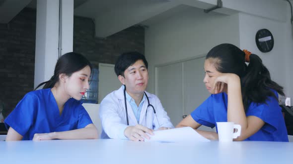 Group of Young Asian Doctor and Nurse Sitting During Break Discussing Serious Patient Case alt