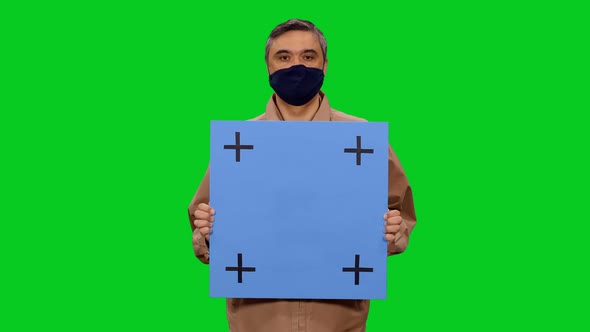 Adult Man In Mask Looking At Camera While Standing With Blue Blank Board