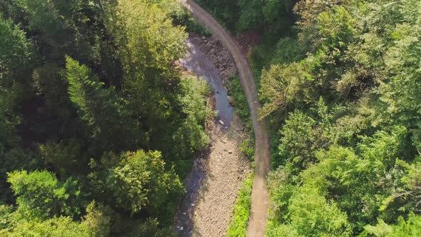 Top View of a Mountain River With Stones on the Bank and Adjacent Green Trees alt